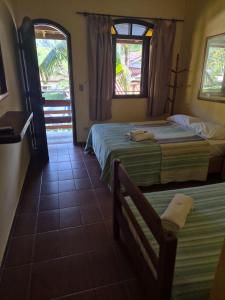 a hotel room with two beds and a window at Hotel Pousada Cavalo Marinho in Boicucanga +132 photos