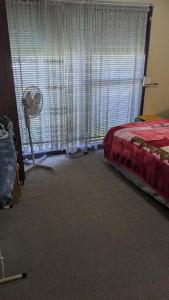 a bedroom with a bed and a window with a fan at BIDWILL GARDENS ON MIDDLETON - 2 Rooms A Private Room with a King-Size Bed or Open Lounge Room Floor Mattress SHARED Bathroom FREE Kitchen Essentials FREE Laundry Facilities Fast WIFI HDTV NETFLIX, YOUTUBE, KAYO Meal and Transport Services Available in Bidwill
