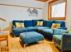 a living room with a blue couch and chairs at Primrose Lodge with Hot Tub near Waterpark and Trails in Chudleigh