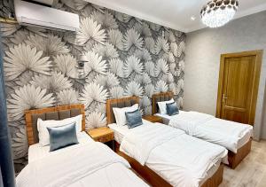 a room with three beds and a wall mural at Mumtoz East Hotel in Bukhara