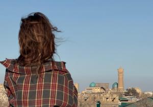 a woman in a plaid shirt looking at a city at Mumtoz East Hotel in Bukhara