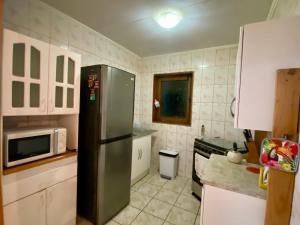 a kitchen with a refrigerator and a microwave at Refugio Escondido in Isla de Maipo