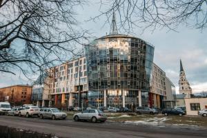 a tall glass building with cars parked in front of it at Riga Riverside Apartment in Rīga