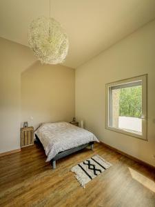 a bedroom with a bed and a window and a chandelier at Maisonnette des vignes in Albertville