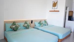 two beds in a room with blue pillows at Happy Island Inn in Virac