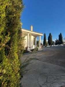 a white house with a hedge in front of it at FINCA EL OLIVAR Casa Rural in Los Corrales