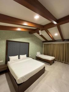 a bedroom with two beds in a room with a ceiling at Amazinn Hotel in Lonavala