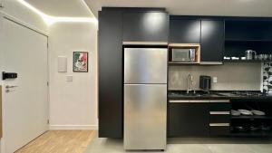 a kitchen with a stainless steel refrigerator and black cabinets at Studio Red 14 - Sorocaba in Sorocaba