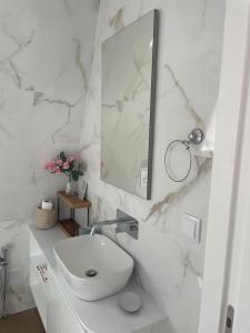 a white bathroom with a sink and a mirror at Casa de Saudade - Refúgio junto ao mar in Paço de Arcos