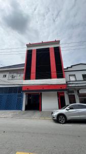 a red and black building with a car parked in front at Hotel Costa Leste in São Paulo