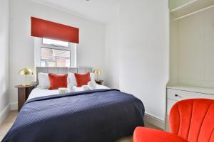 a bedroom with a bed and a red chair at Cosy 3-Bedroom House Near Caerphilly Castle in Caerphilly