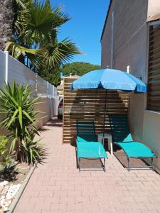 two chairs and an umbrella on a patio at Casa Littoral in Le Grau-dʼAgde