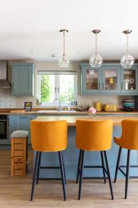 a kitchen with blue cabinets and orange bar stools at Nest Lodge by The Butler Collection in Pulborough