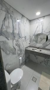 a bathroom with a toilet and a sink and a mirror at Hotel Costa Leste in São Paulo