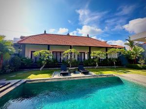 a house with a swimming pool in front of a house at Plawa Bali Guest House in Canggu