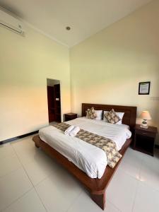 a bedroom with a large bed with white sheets and pillows at Plawa Bali Guest House in Canggu