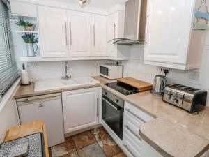 a kitchen with white cabinets and a sink at Trelessy Lodge in Amroth +13 photos