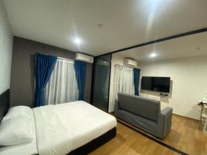 a bedroom with a bed and a couch and a television at Caesar's Suite Condo Korat - Pool Renovation in Ban Pra Dok