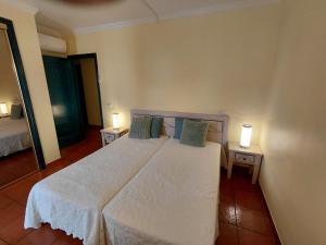 a bedroom with a large white bed with two lamps at Apartamento Parque dos Reis I in Monte Gordo +14 photos