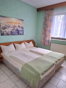a large bed in a bedroom with a window at Hotel Pappelhof in Weidenbach