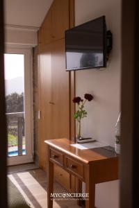 a vase of flowers on a table with a television at Quinta Anna Horvath in Vale de Cambra