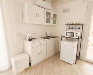 a white kitchen with a sink and a microwave at Sole & Luna in Elmas