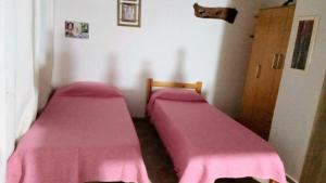 two beds in a room with pink sheets at Complejo El Tala in Mina Clavero