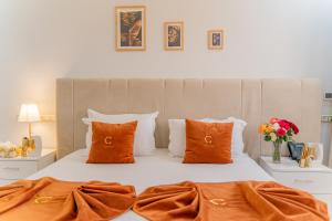 a bedroom with a white bed with orange pillows at Hotel Golden Sunset Dakhla in Dakhla