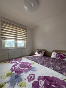 a bedroom with a bed with purple flowers on it at Apartman MARIJA in Pale