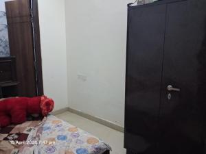 a red teddy bear laying on a bed next to a cabinet at SG Homestay in Amritsar