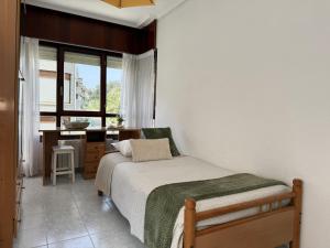 a bedroom with a bed and a desk and a window at Apartamento Salceda - 6901 in Noja