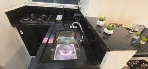 a kitchen counter with a sink and a stove at Arandura Chalés maresias 04 in São Sebastião