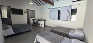 a room with two beds and a table with a desk at Arandura Chalés maresias 04 in São Sebastião