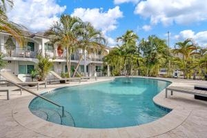 a swimming pool with palm trees and buildings at Beachside Studio w Pool Access Steps from the Shore in Pompano Beach