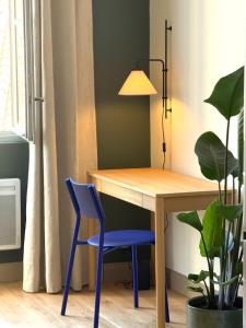 a desk with a blue chair and a lamp at Appartement calme et lumineux au cœur d'Arles in Arles