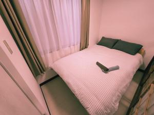 a small bed in a small room with a window at Tokyo Nukumori Lodge in Tokyo