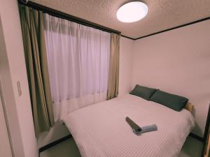 a small bed in a room with a window at Tokyo Nukumori Lodge in Tokyo
