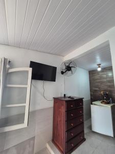 a room with a ceiling with a fan and a dresser at Pousada Casa Da Arara suíte 104 in Saquarema