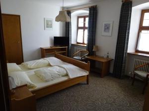 a bedroom with a bed and a desk and windows at Schloß-Hotel Hirschau in Hirschau