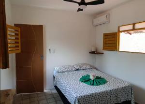 a bedroom with a bed with a green bow on it at Kitnet com veranda in Conde +11 photos