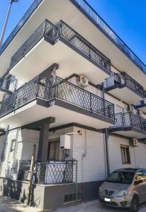 a building with balconies and a car parked in front at B&B Le Corti in Caserta