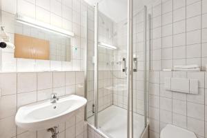 a white bathroom with a sink and a shower at Jägerheim in Nuremberg +40 photos