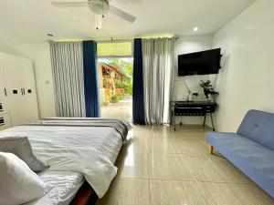 a bedroom with a bed and a couch and a television at private villa with private pool in Aborlan
