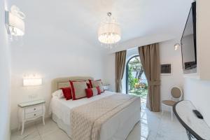 a white bedroom with a bed and a chandelier at Villa Amore Amalfi Coast in Ravello
