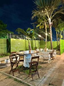 a picnic table with chairs and palm trees at night at Pousada Jardins in São Luís
