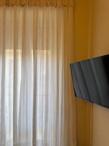 a window with a white curtain and a tv at Casa del Corso Apartments in Avola