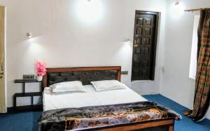 a bedroom with a bed with white sheets and a window at The Holt Gardens in Srinagar +7 photos