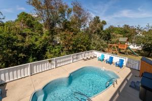a swimming pool on a patio with chairs and a playground at Casa Bella - Duck, Bayberry Bluffs, Ocean View, 500 Yds to Beach, Pool, Hot Tub, Playset, Pets OK in Duck