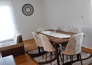 a dining room table with chairs and a clock on the wall at Vikendica Danilo in Banja Luka