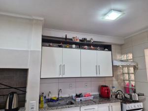 a kitchen with white cabinets and a sink at 1 dorm aconchegante em apto compartilhado com a moradora in Santa Rosa